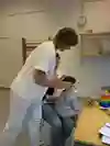 Ett barn i två års åldern sitter i sin förälders knä medans en BHV-sjuksköterska undersöker barnets huvudform.